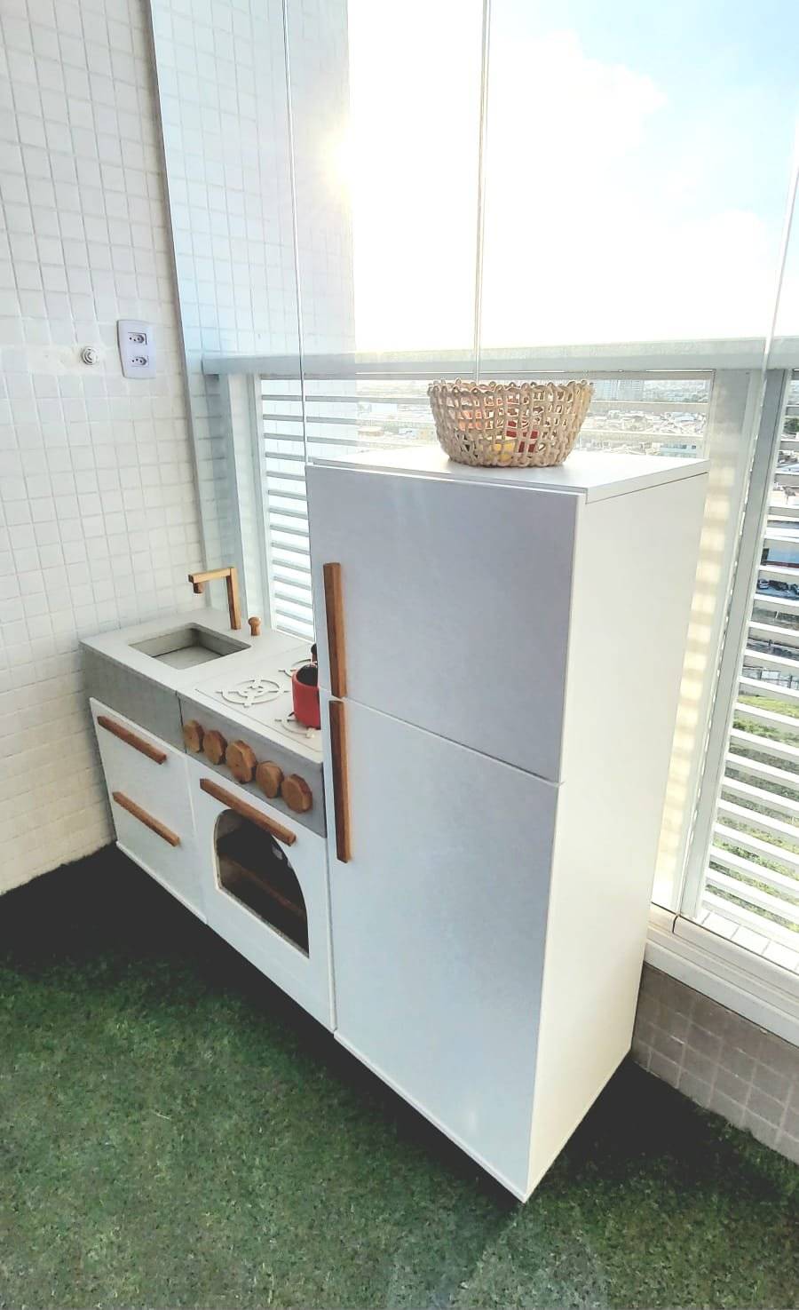 Cozinha de brinquedo branca, perto da janela com plantas