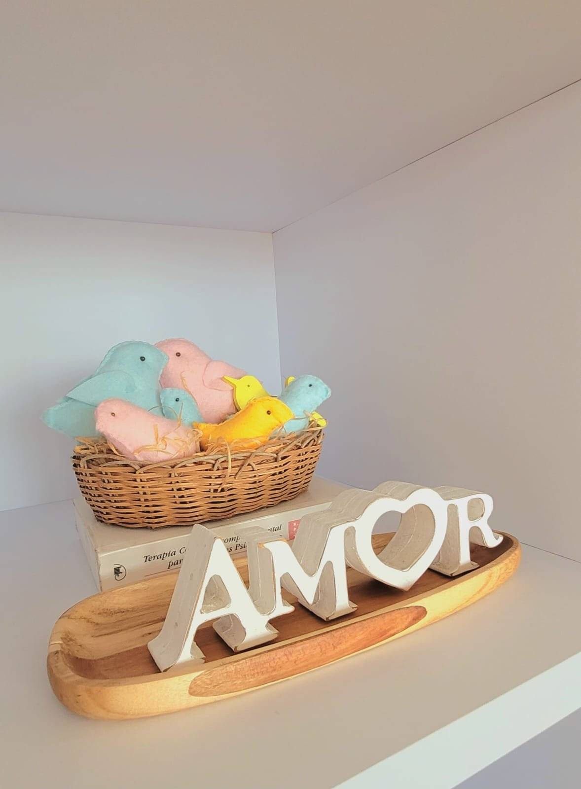 Cesto de brinquedos de crochê em tons pastel sobre a palavra AMOR em madeira, no consultório
