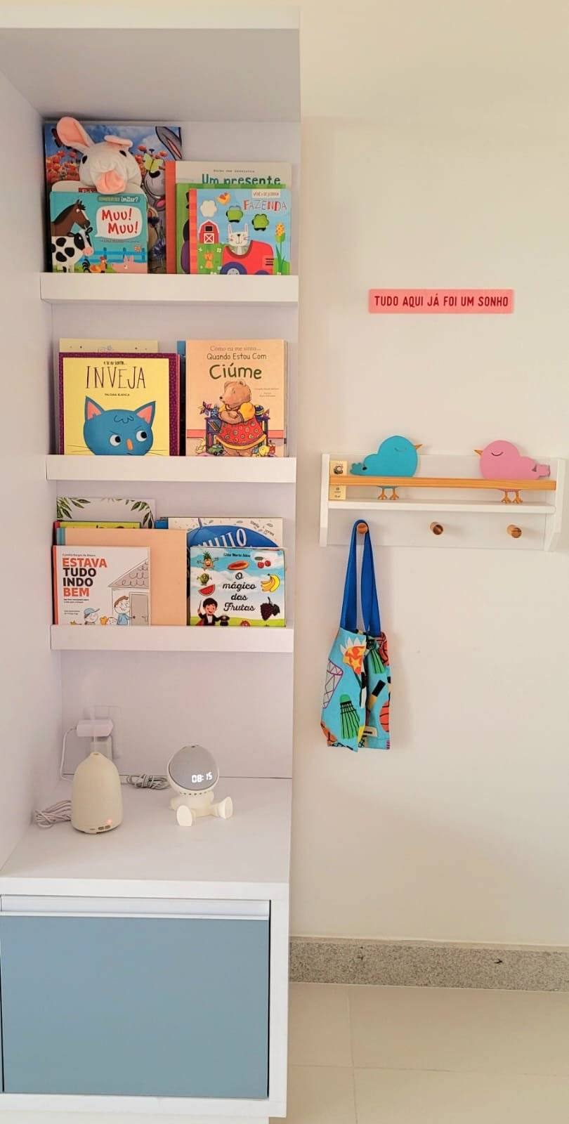 Estante branca organizada com livros infantis, jogos e caixas