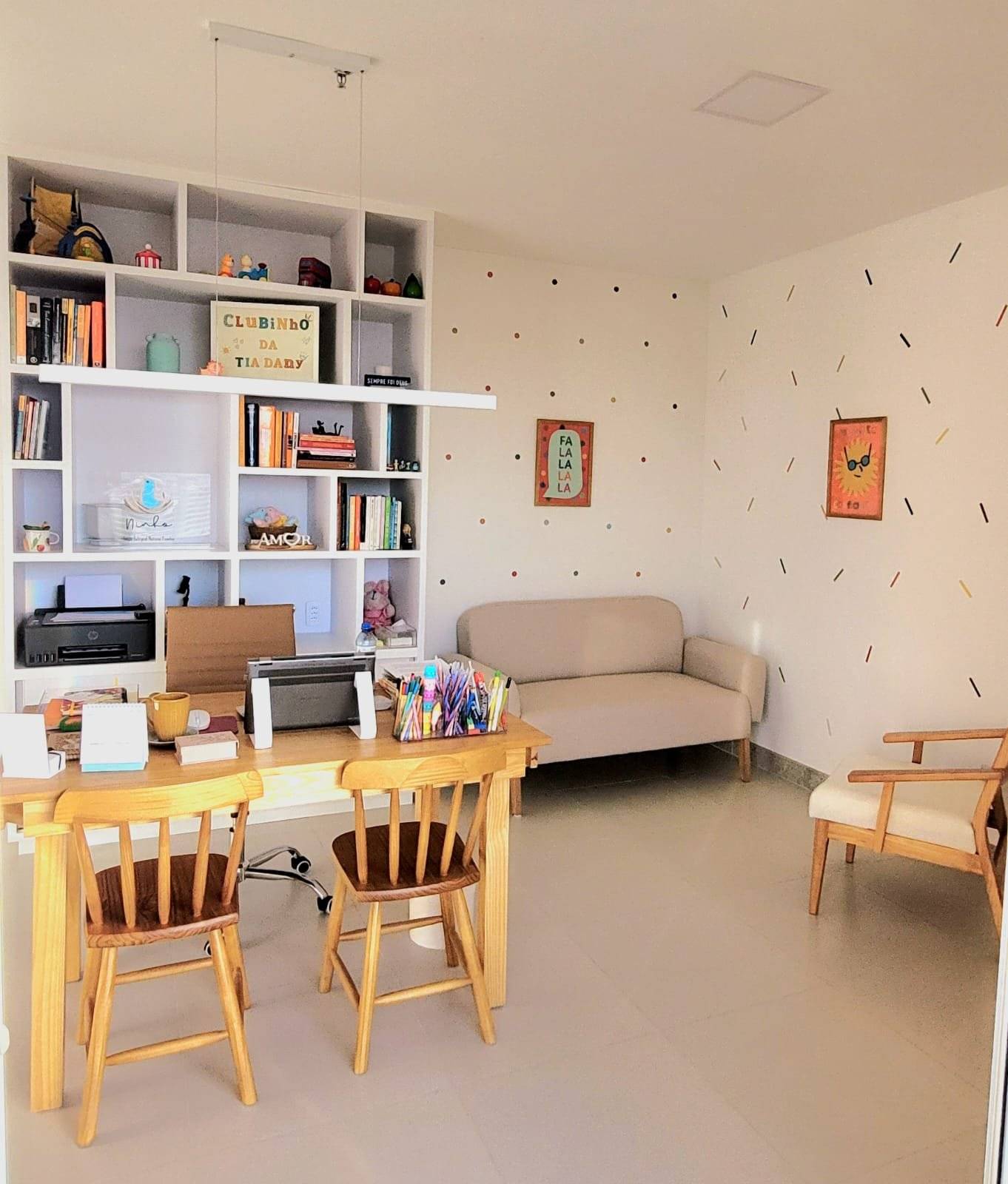 Sala do consultório com mesinha infantil, estante de livros e brinquedos e sofá para os pais